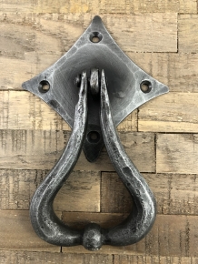 Beautiful design is this door knocker wrought iron for on the rustic wooden door.