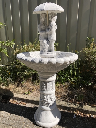 Gartenbrunnen voller Steine mit Kindern unter einem Regenschirm, sehr schön!