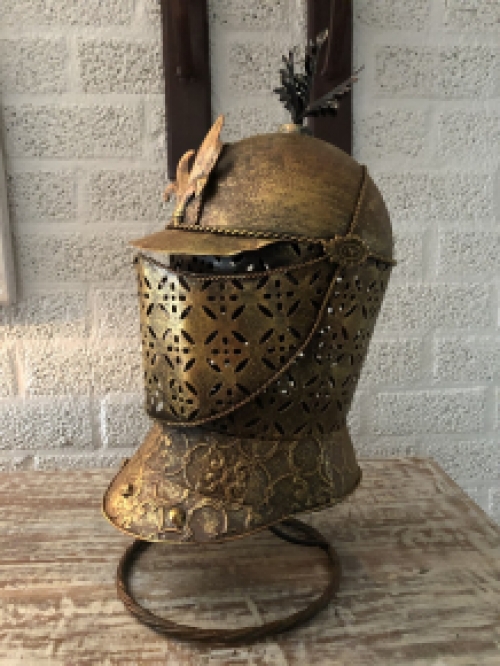 A beautiful metal brass knight helmet on stand.